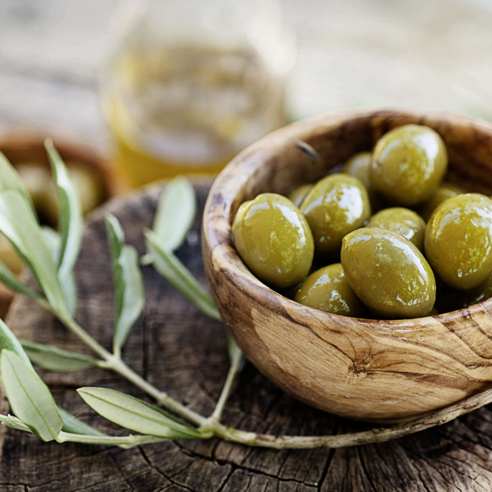 Fresh olives and olive oil  on rustic wooden background. Olives in olive wood.